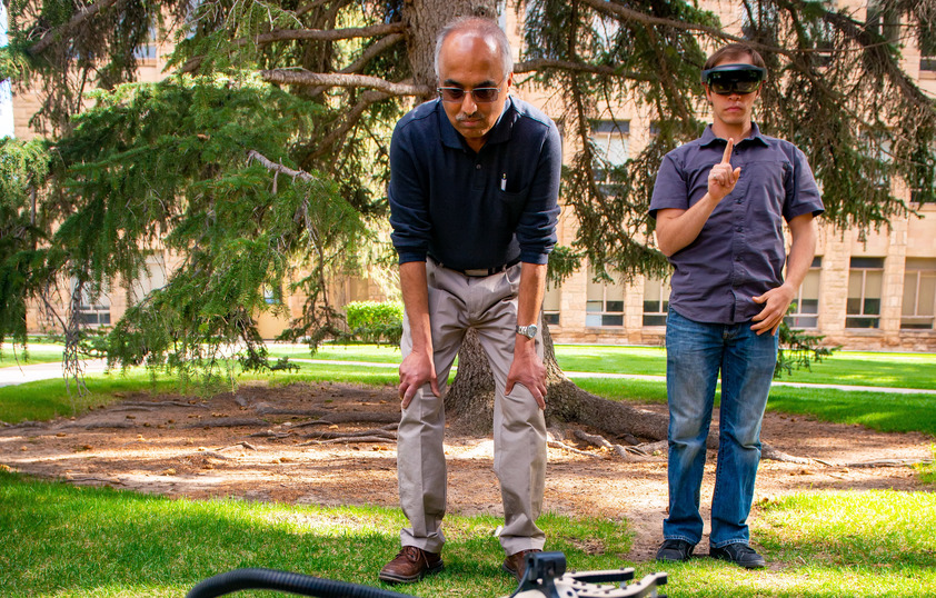 Professor and student working together on a robot outside