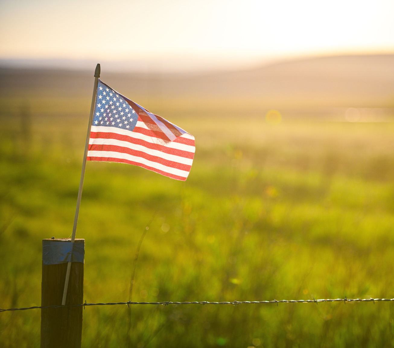 American Flag taped on barbed wire fence with duck tape