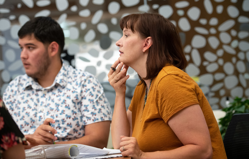 A student and faculty member listen to others speak.