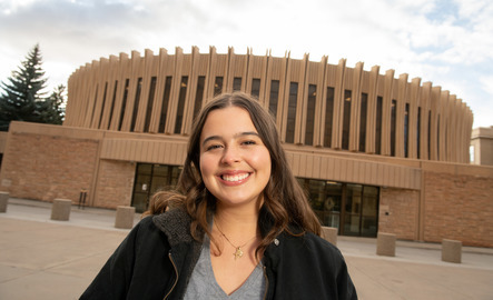 A student smiles in front of the UW classroom building