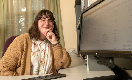 An advisor smiles next to their computer