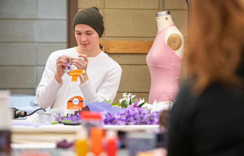 Student pins a flower on a piece of clothing during class