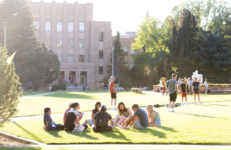 Students sit in a circle on the lawn