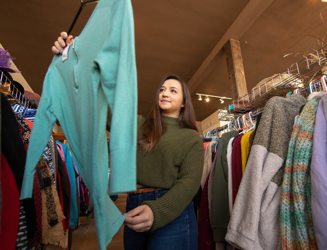 A student examines a piece of clothing at a store