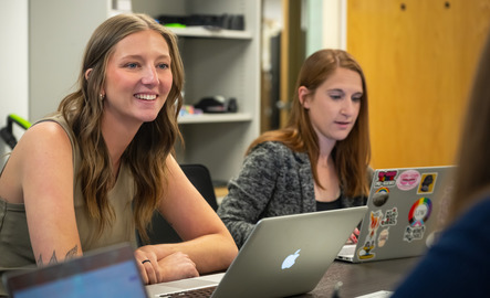 Two computing students work on their laptops during class
