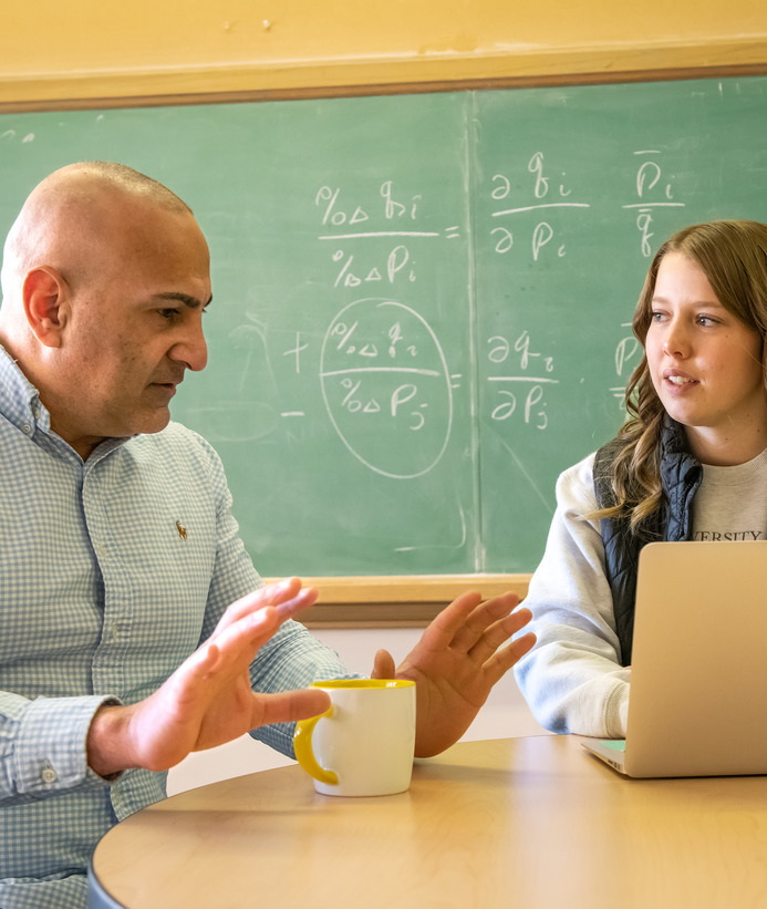 An applied economics professor and student discuss something in class