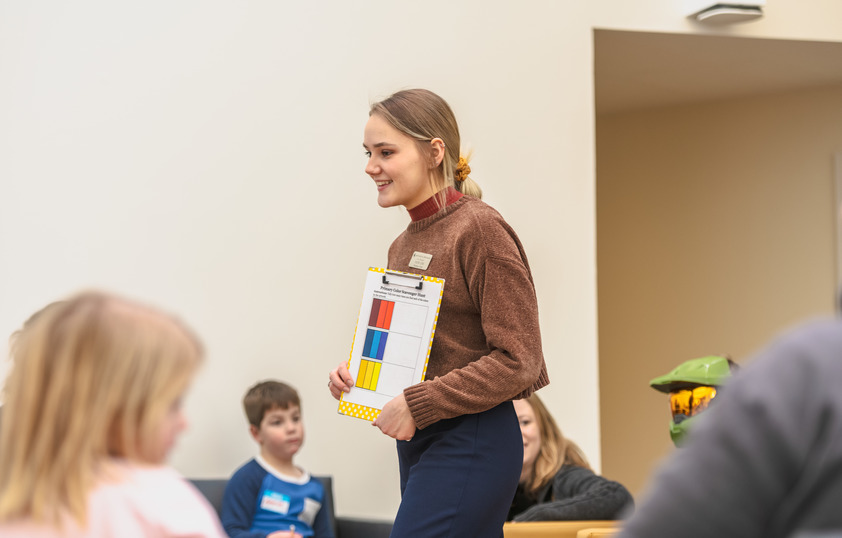 an art teacher is smiling as a group of children listen