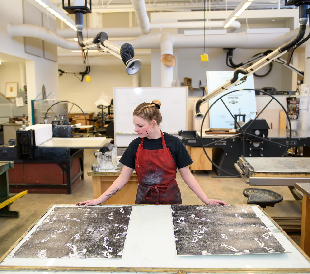 an artist looks at prints in a printmaking studio classroom