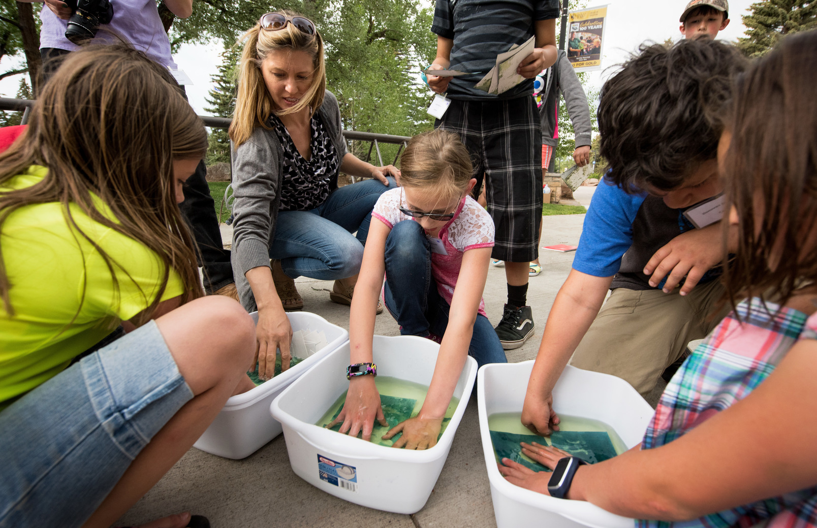 a group of students working on an art activity while a teacher assists