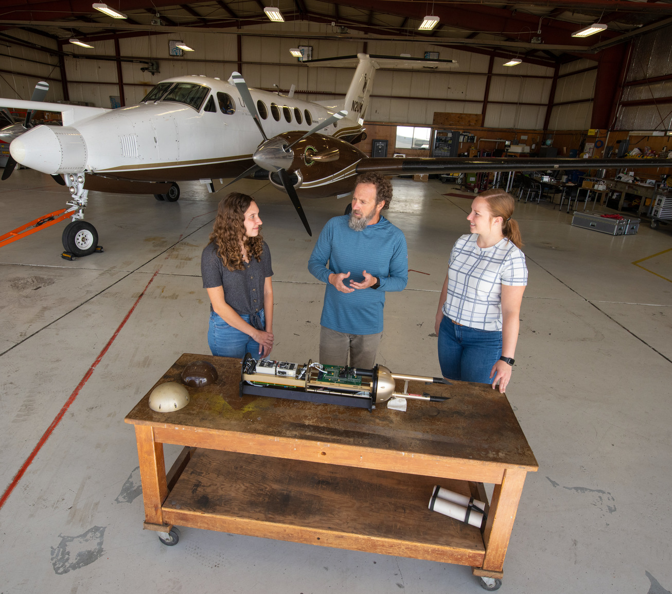 Professor teaching two students about an airplane part