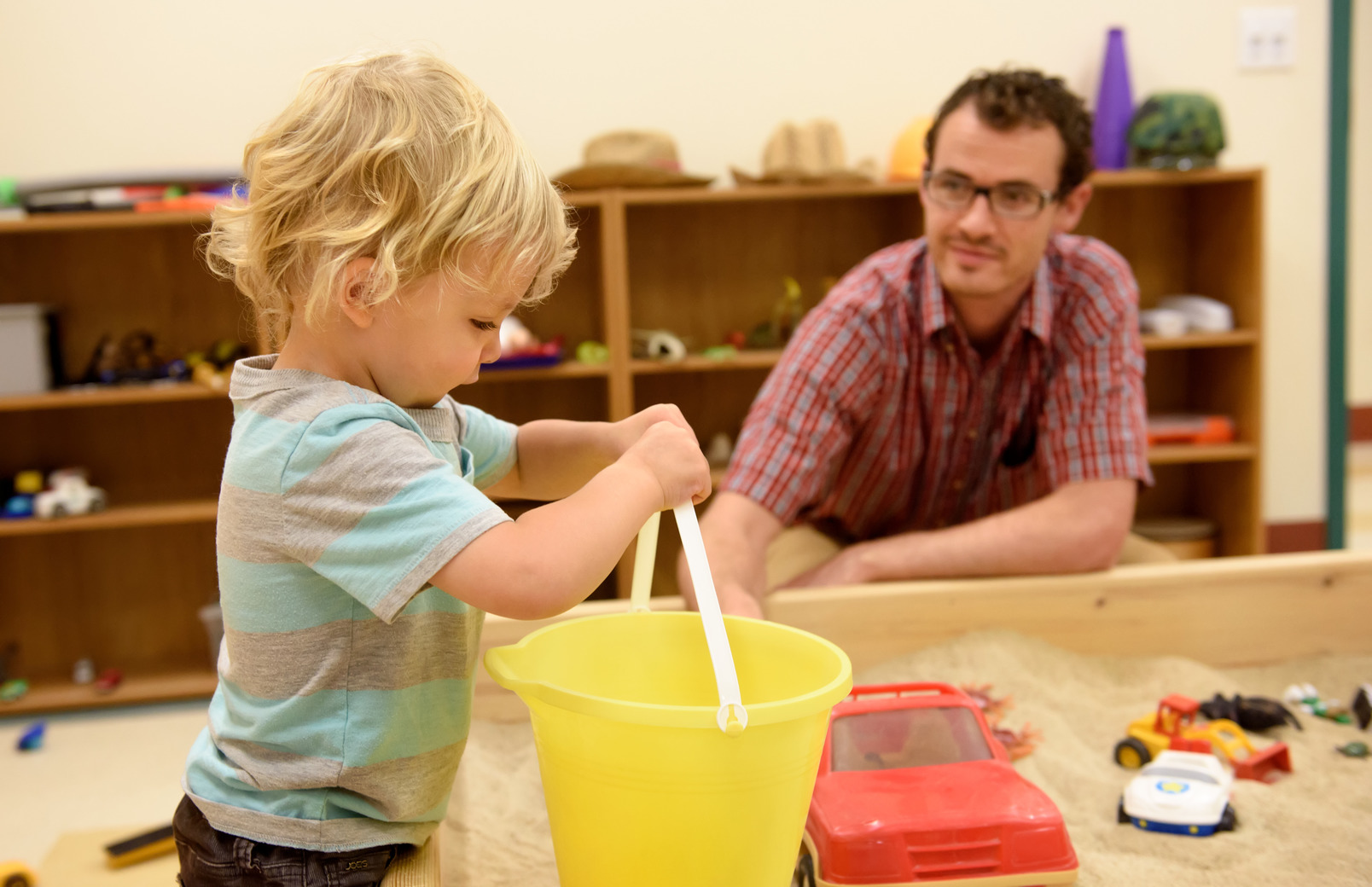 Teacher working with student in an indoor sandbox