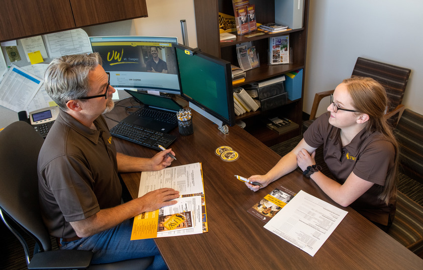 Student and staff memeber sitting at desk together