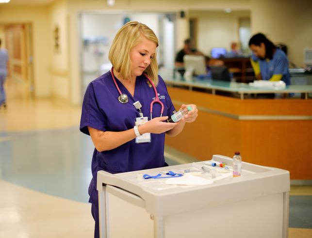 A nursing at her station examining a vial