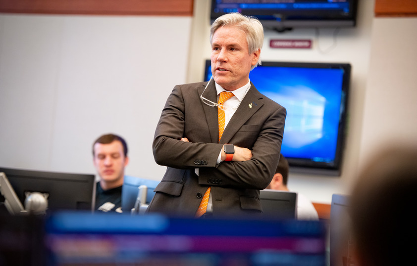 A professor listens to students in their classroom.