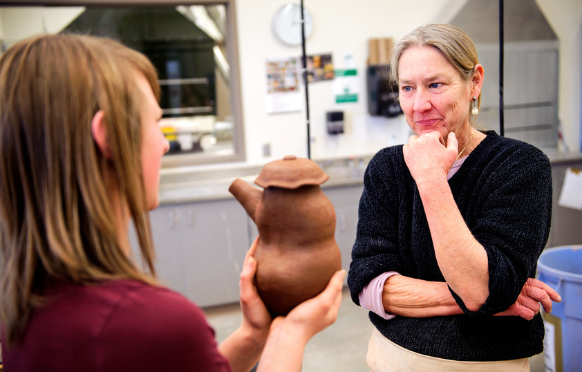 Professor looking at cermaics student's pottery