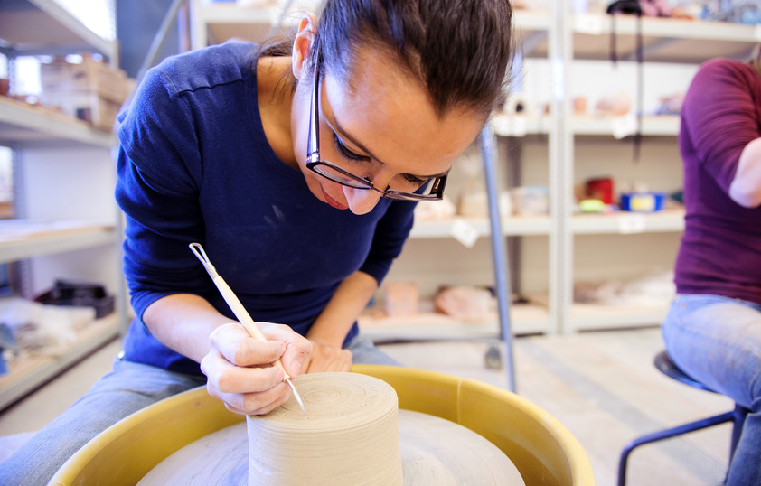 Ceramics student sculpting on a pottery wheel