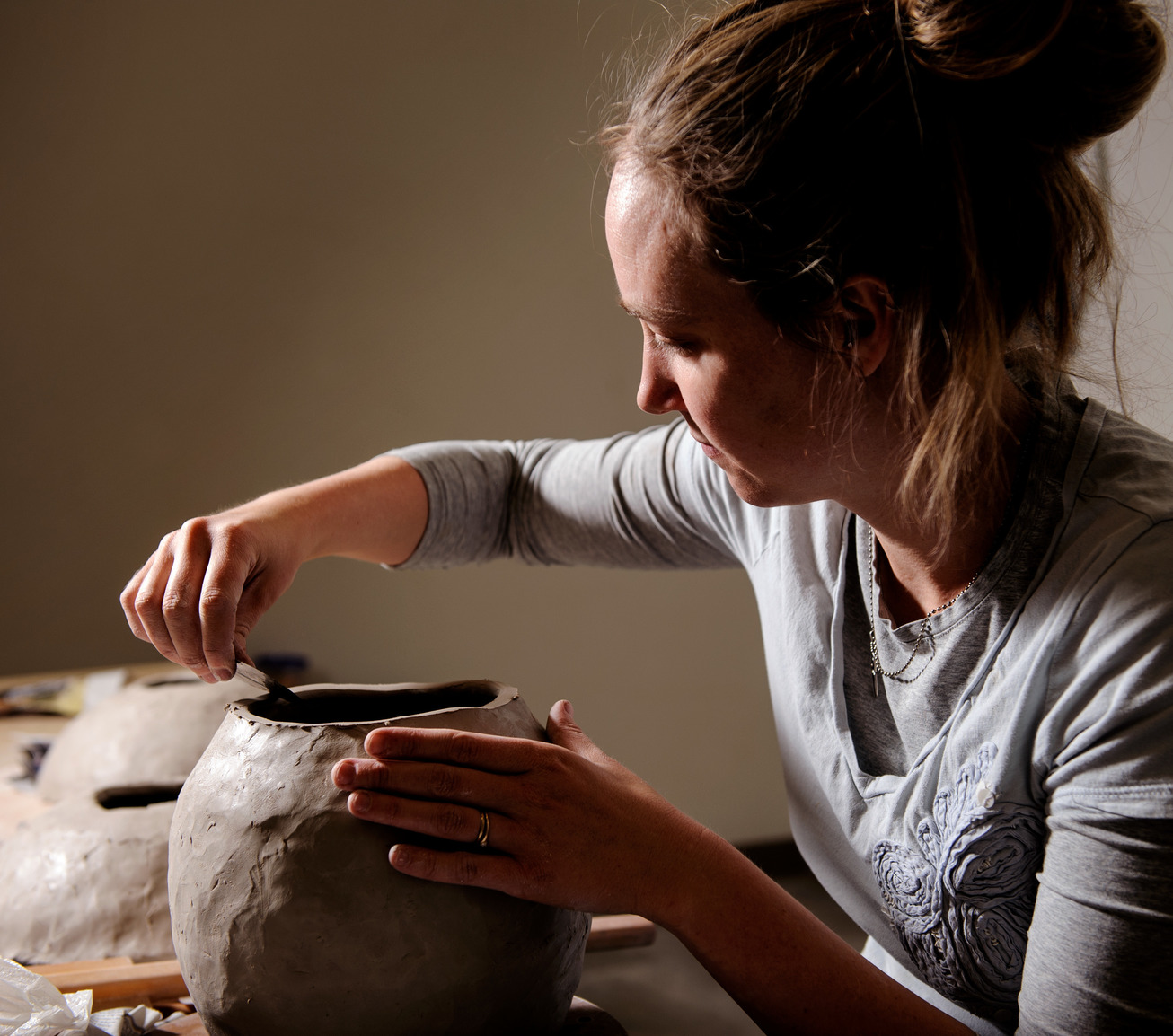 Ceramics student sculpting the top of a clay vase