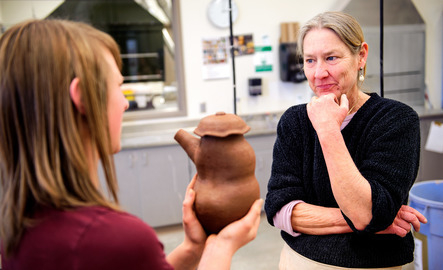 Professor looking at cermaics student's pottery