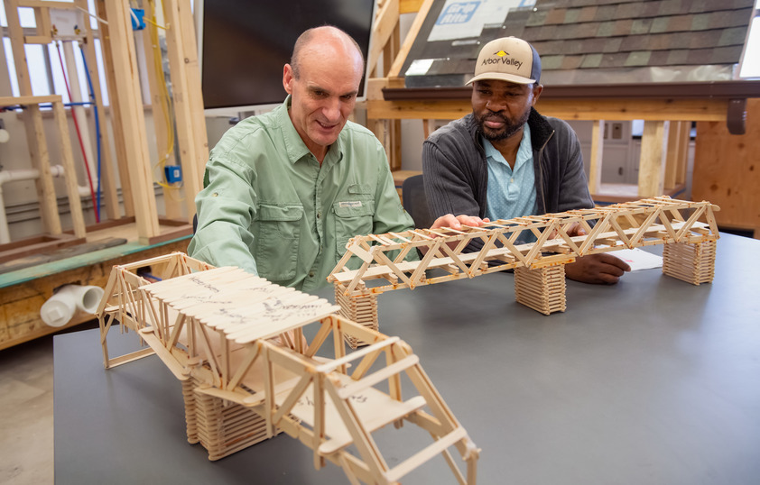 Professor and student looking at popsicle stick models