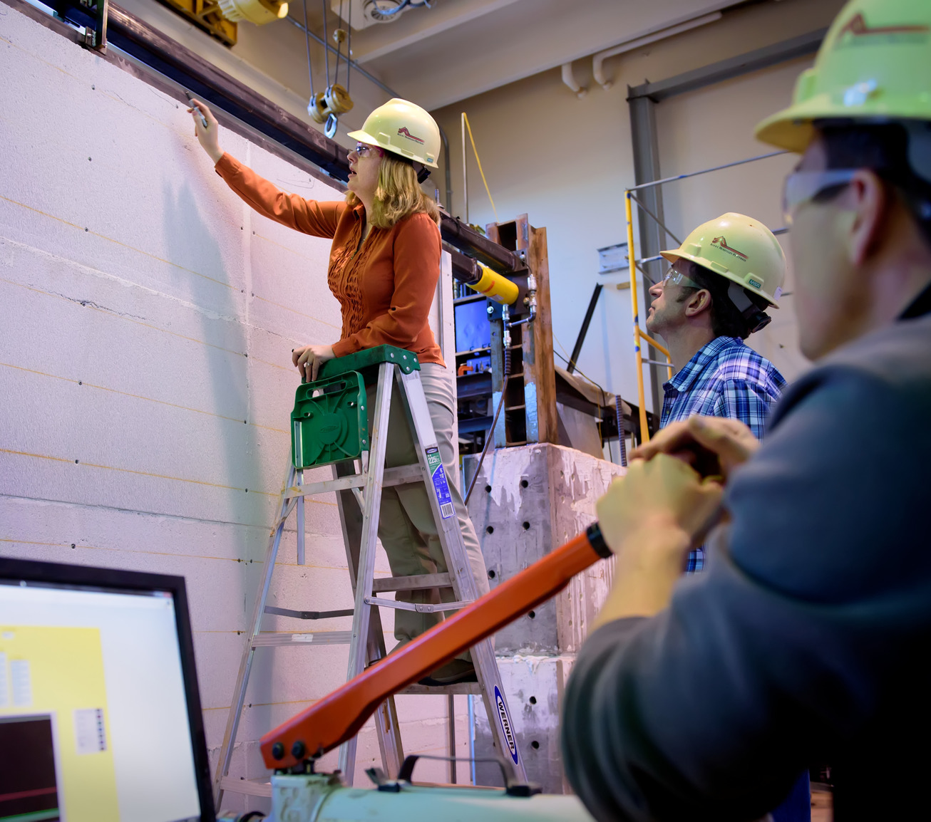 Students and professor working together in lab with hard hats on