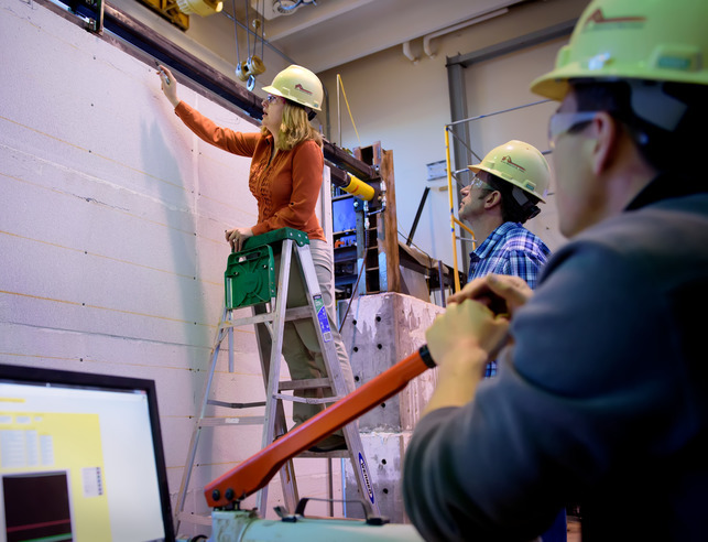 Students and professor working together in lab with hard hats on