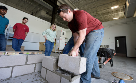 Civil engineering faculty members and students assembling a wall full of cinder blocks