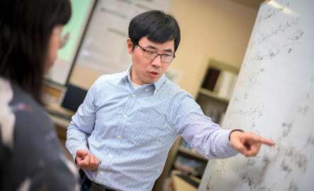 Faculty member pointing at white board