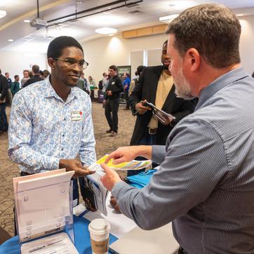 Two people shake hands at a career fair