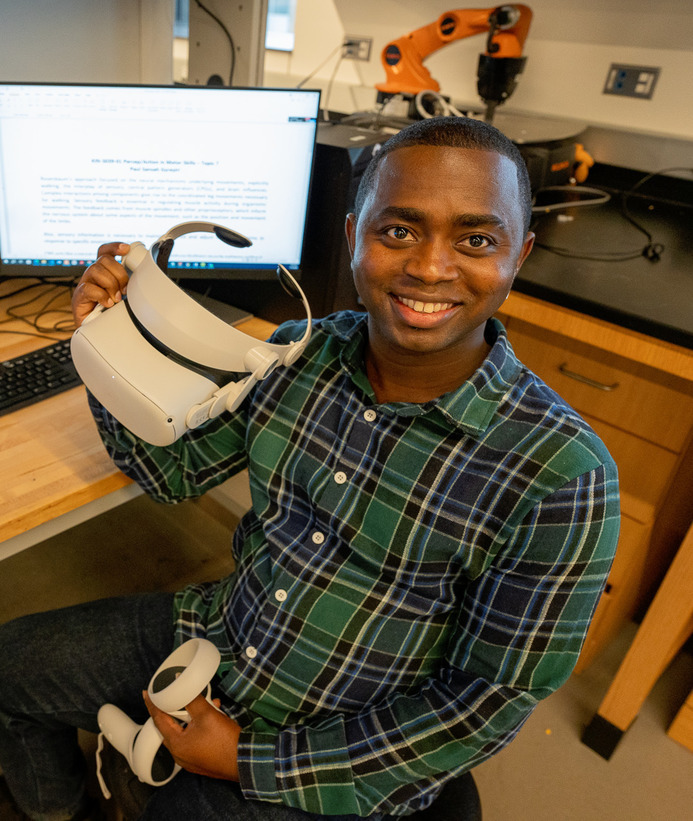 An electrical and computer engineering student holding up V.R. goggles