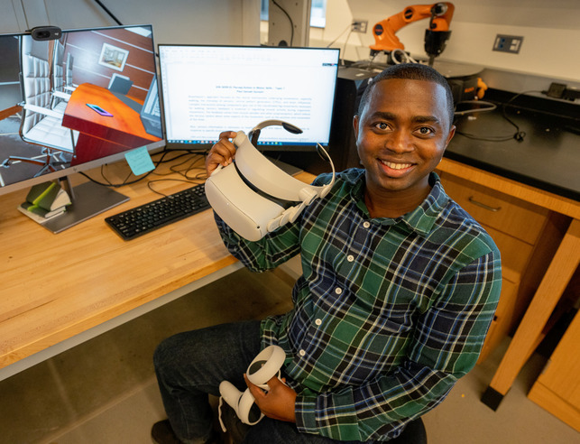 An electrical and computer engineering student holding up V.R. goggles