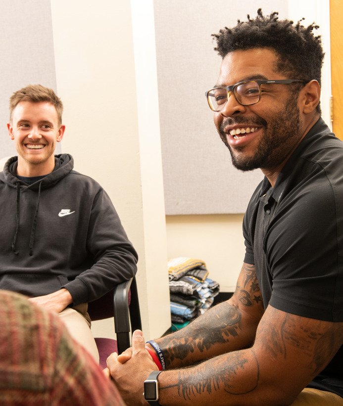 A counselor and group therapy participant laugh during a therapy session