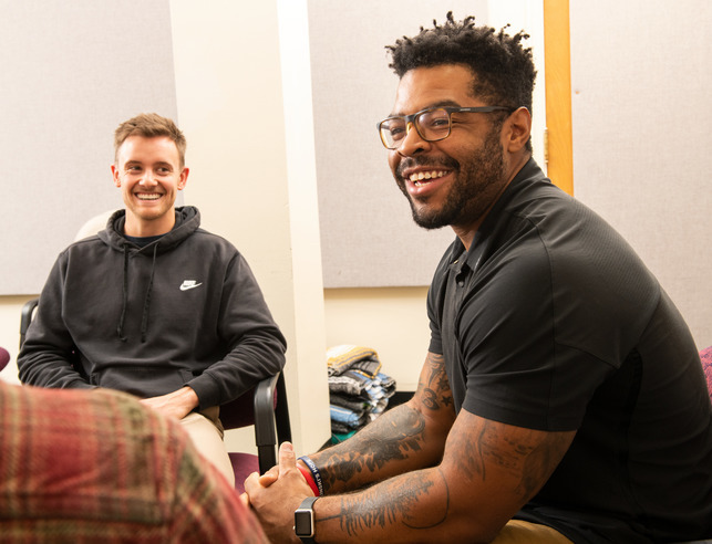 A counselor and group therapy participant laugh during a therapy session