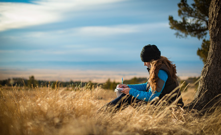 A student writes outside with a scenic landsape