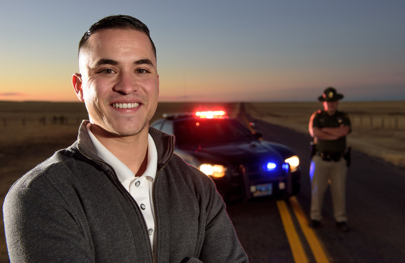 Two state troopers stand in front of a police car