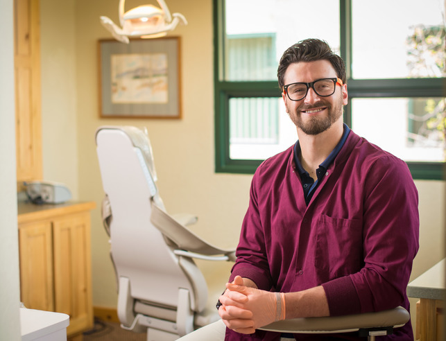 A former UW student stands in their dental exam room