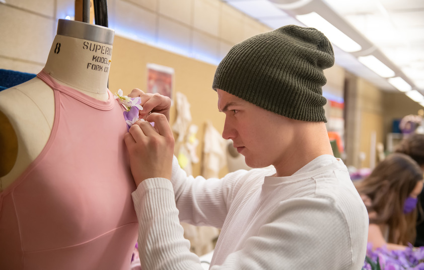 Student pinning flower to outfit on a mannequin