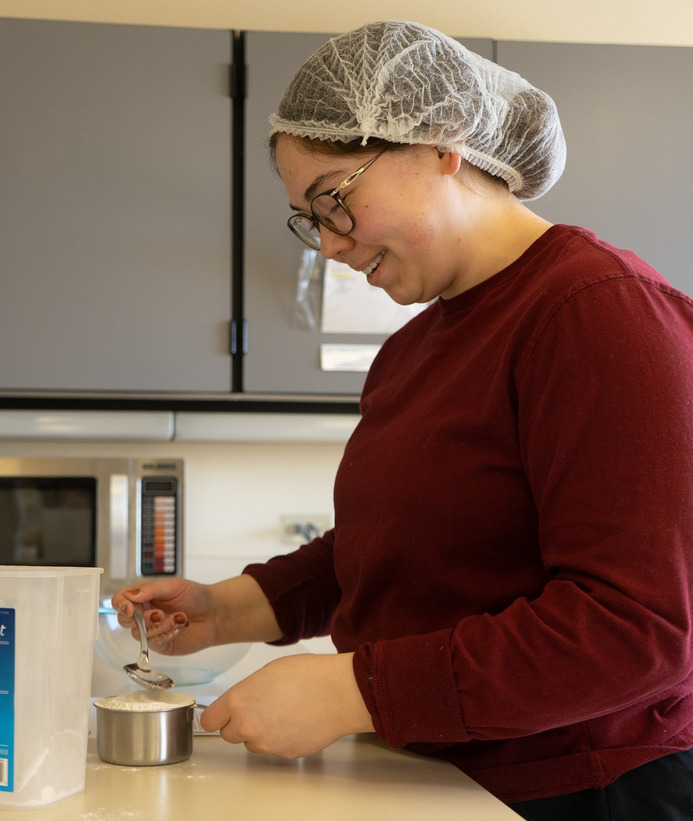 A dietetics student in class measuring flour