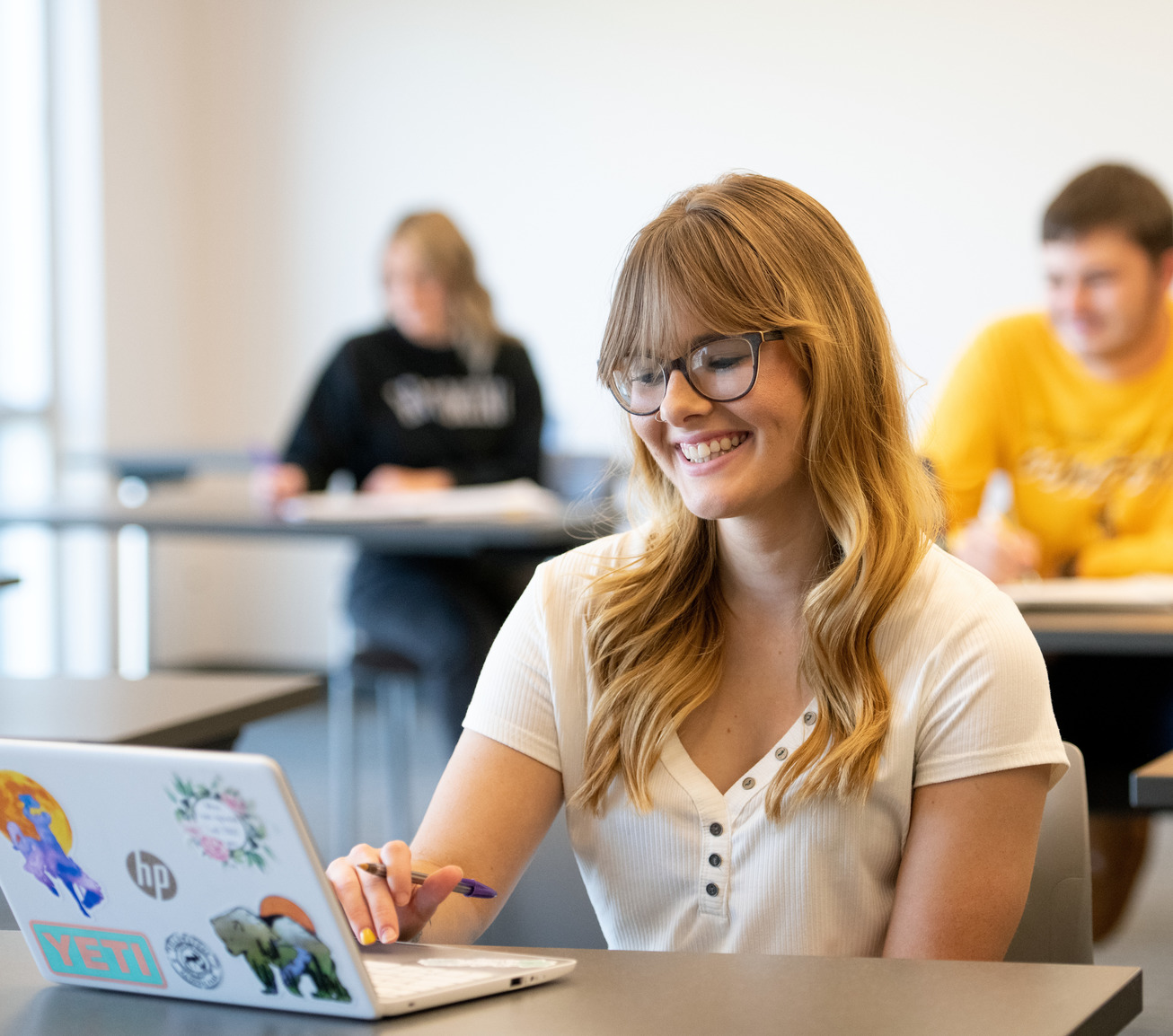 Student smiling at laptop in class