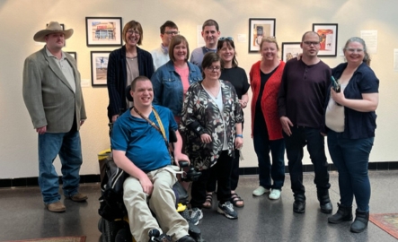 A group of people smile for a photo at an art exhibit