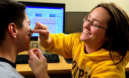 A doctorate students places monitoring device on a subjects face and head