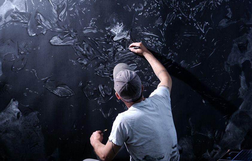 Professor sketching on a large black campus with a white pencil