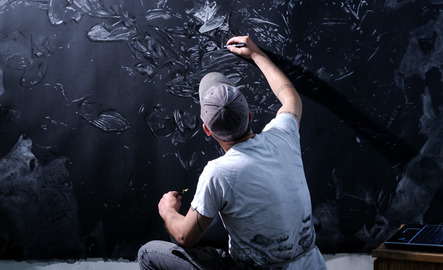 Professor sketching on a large black campus with a white pencil