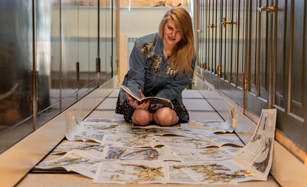 A student examines an array of newspapers with dried plants in them