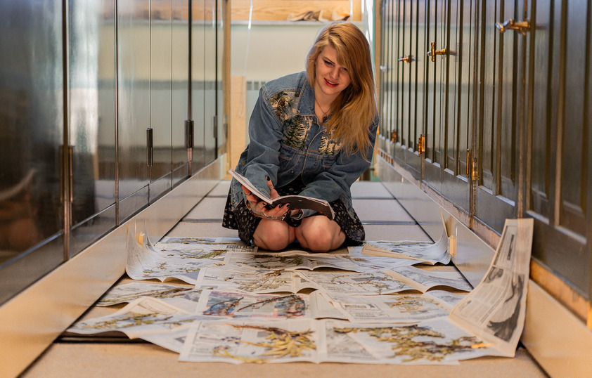 A student examines an array of newspapers with dried plants in them