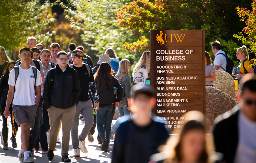 Students walking outside the College of Business sign