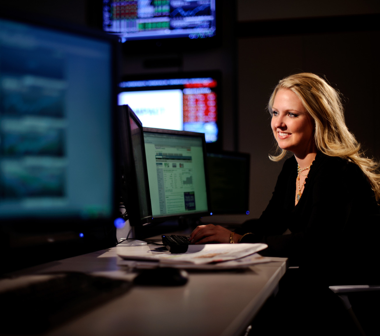 An economist looks at two computer screens while smiling