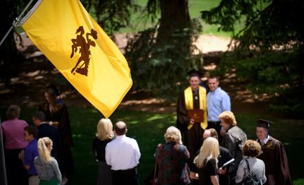 UW flag in front of graduates taking photos