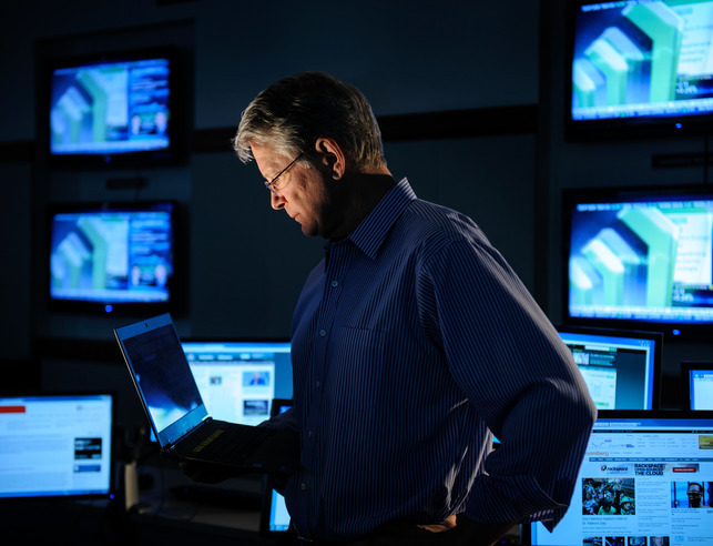 An economics professor in the stock room looking at his laptop