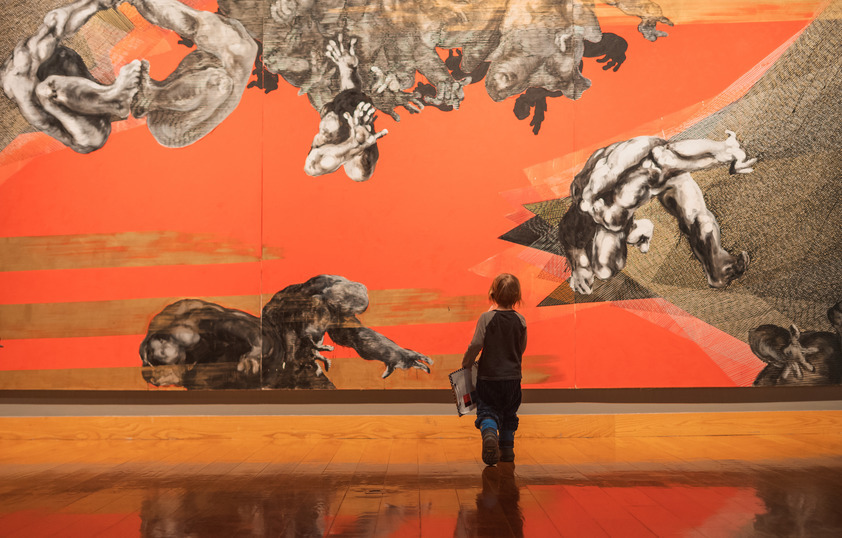 A child walks towards a bright orange artistic wall