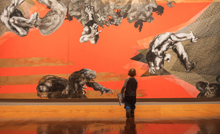 A child walks towards a bright orange artistic wall